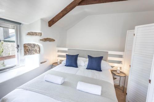 une chambre avec un lit avec des oreillers bleus et une fenêtre dans l'établissement Cosy 1 bedroom Cottage - Great location & Parking, à Penzance
