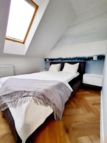 a bedroom with a large white bed with a window at Apartament Północne Mazury in Węgorzewo