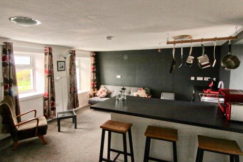 cocina y sala de estar con barra y sillas en Whitewave Apartment en Monkstadt