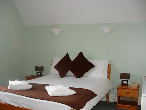 1 dormitorio con 1 cama con sábanas blancas y almohadas marrones en Bath House Hotel, en Ilfracombe