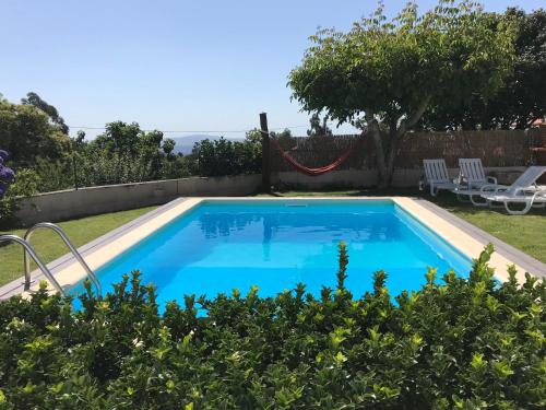 a swimming pool with a hammock in a garden at Ribeirinho da Serra in Penela