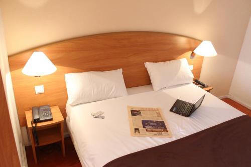 a hotel room with a bed with a book and a phone at Central Hotel in Créteil