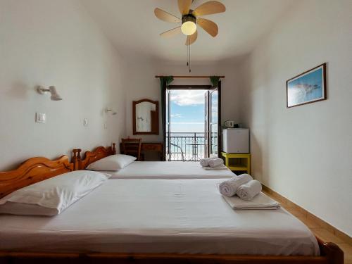 a bedroom with two beds and a window with a view at Pansion Giannis Perris in Kokkari