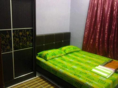 1 cama con edredón verde en una habitación en HOMESTAY CAHAYA PUTERI, en Tangga Batu