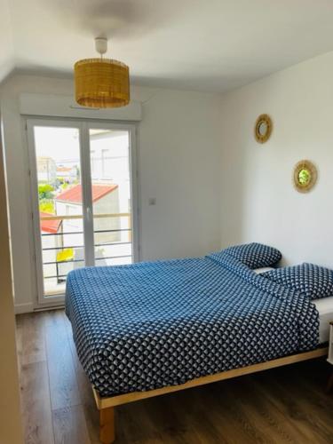 une chambre avec un lit bleu et une fenêtre dans l'établissement La maison des hirondelles, à Berck-sur-Mer