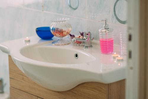 ein weißes Waschbecken mit einer Glasschüssel und einer Flasche in der Unterkunft casa mare incantevole in Alghero