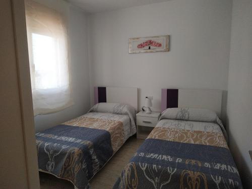 1 dormitorio con 2 camas y ventana en PROALMAR, chalet 17, en Peñíscola