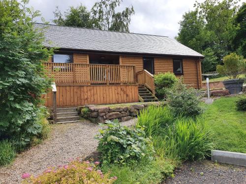 a log cabin with a deck and a yard at Upper Rosemount Lodge in Blairgowrie