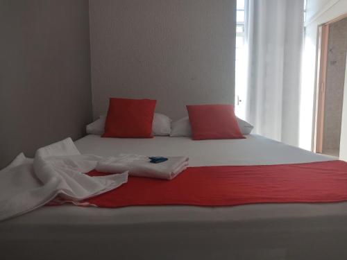 a bed with red and white sheets and a window at Hotel Central in Jacareí