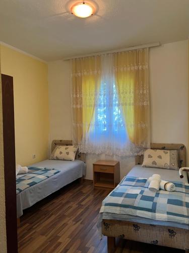 a bedroom with two beds and a window with curtains at Apartments Mujovi in Bar