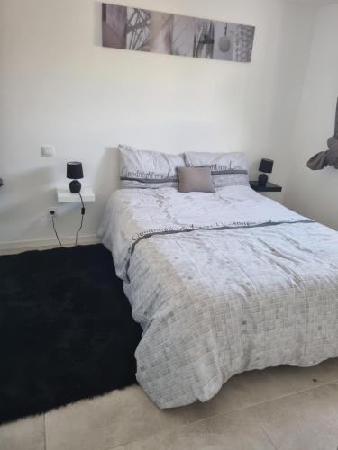 a white bedroom with a large bed with a blanket at appartement in Marmande