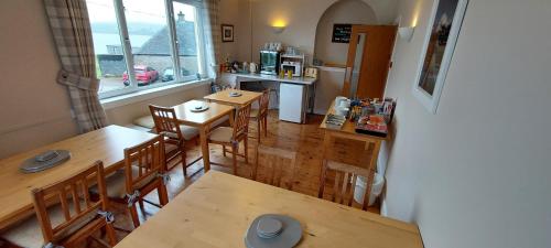 uma cozinha e sala de jantar com mesas e cadeiras de madeira em Cala Sith Guesthouse em Port Ellen