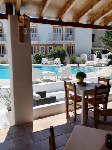 une terrasse avec une table, des chaises et une piscine dans l'établissement Katerina Apartments, à Kalymnos