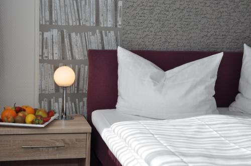 a bed with a bowl of fruit and a table with a lamp at Landhotel Karrenberg in Kirchberg