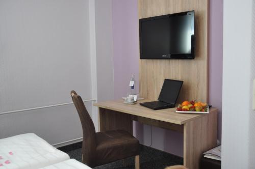 a hotel room with a desk with a laptop and a tv at Landhotel Karrenberg in Kirchberg