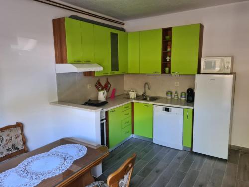 cocina con armarios verdes, mesa y nevera en Apartman Darko en Solin