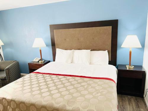 a hotel room with a bed and a chair and lamps at Super 8 by Wyndham Fort Scott in Fort Scott