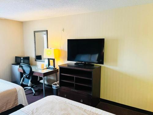 a hotel room with a television and a desk with a bed at Super 8 by Wyndham Fort Scott in Fort Scott