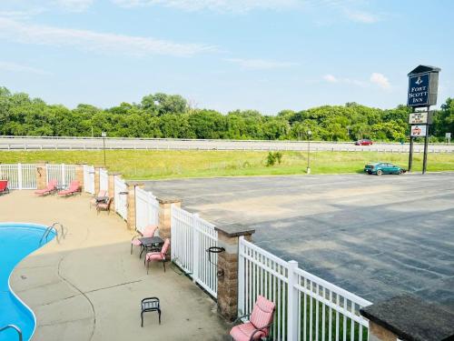 a parking lot with pink chairs and a pool at Super 8 by Wyndham Fort Scott in Fort Scott