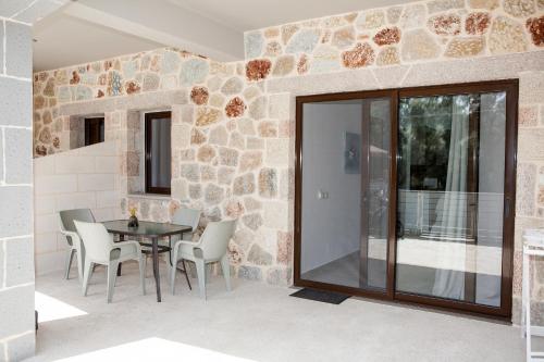 a dining room with a table and chairs and a stone wall at Casa Di Pietra in Palaiokatoúna