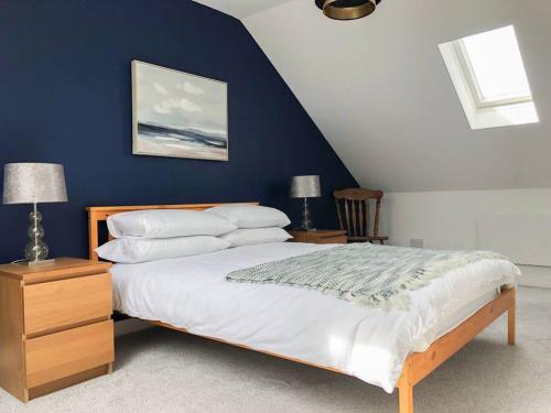 a bedroom with a bed and a blue wall at Light & Spacious Loch Lomond Apartment in Alexandria