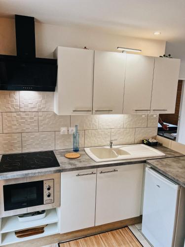 a kitchen with white cabinets and a sink at chalet des Illes SAINT MARTIN IIII in Prat-et-Bonrepaux