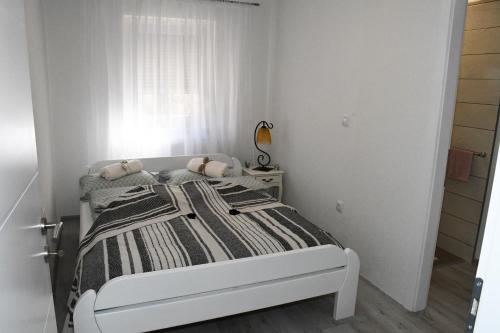 a white bedroom with a bed and a window at Apartment Sarajlic in Prijedor