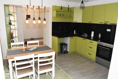 una cocina con armarios verdes, mesa y sillas en Apartment Sarajlic, en Prijedor