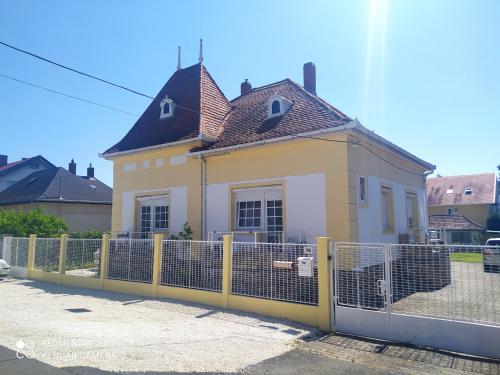 uma casa amarela e branca atrás de uma cerca em Villa Vanília em Keszthely