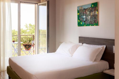 a bedroom with a large white bed and a balcony at Luna Minoica Suites and Apartments in Montallegro