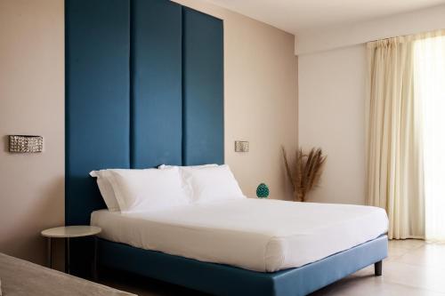 a bed with a blue headboard in a room at Luna Minoica Suites and Apartments in Montallegro