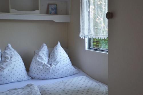 a bed with white pillows on it with a window at Domki holenderskie ,, Latający Holender" in Dębki