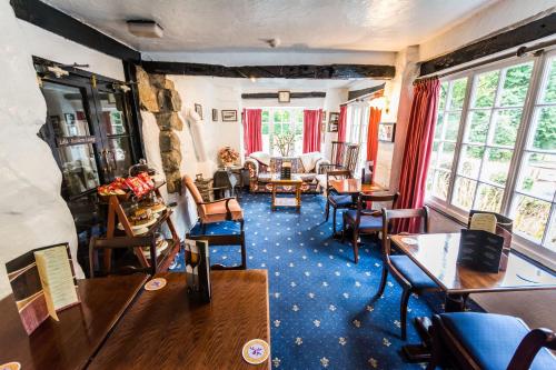 sala de estar con mesas, sillas y ventanas en Gwesty Minffordd Hotel, en Tal-y-llyn