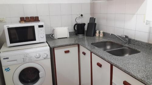 a kitchen with a sink and a washing machine at Espacio C Av Poeta Lugones GRAN VISTA in Cordoba