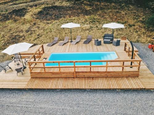 una piscina con sillas y sombrillas en una terraza de madera en chalet des Illes MADAGASGAR II, en Prat-et-Bonrepaux