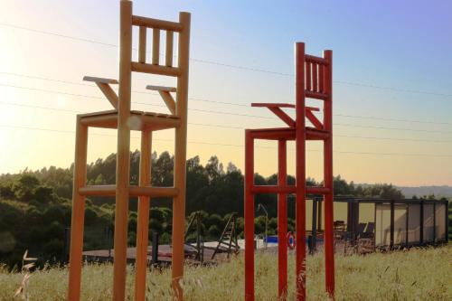 two large wooden chairs sitting in a field at Naturarte Rio - Duna Parque Resorts & Hotels in Vila Nova de Milfontes