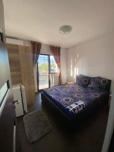 a bedroom with a bed with a blue comforter and a window at Vila Ale in Mamaia Sat/Năvodari