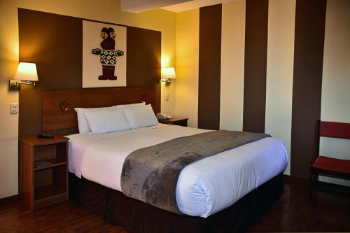 a hotel room with a large bed and a chair at Intiqa Hotel in Puno