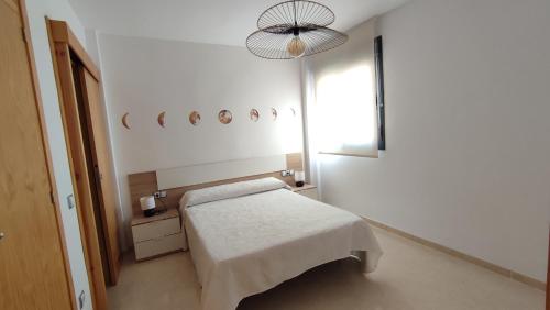 Habitación blanca con cama y lámpara de araña. en Apartamento Residencial Colinas del Golf, Envía, Almería, en La Envía