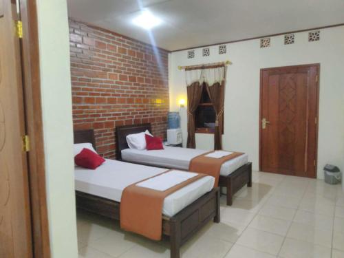 a bedroom with two beds and a brick wall at Penginapan Homestay Mudiyono Syari'ah in Borobudur
