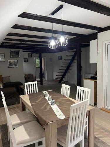 a dining room with a wooden table and white chairs at Zavojsko jezero - Vila Jezero in Pirot