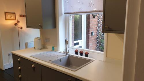 a kitchen with a sink and a window at Beautiful Garden Apartment in Leafy St Leonards 5 Mins to Beach in St. Leonards