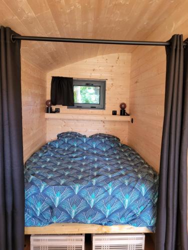 uma cama num pequeno quarto numa pequena casa em Roulotte Escapade nature à Morainville em Morainville-près-Lieurey