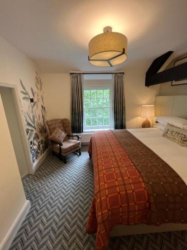 a bedroom with a bed and a chair and a window at Royal Oak Hotel in Rosthwaite