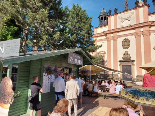 a group of people standing around a green building with a clock tower at Apartments Rose Garden in Děčín