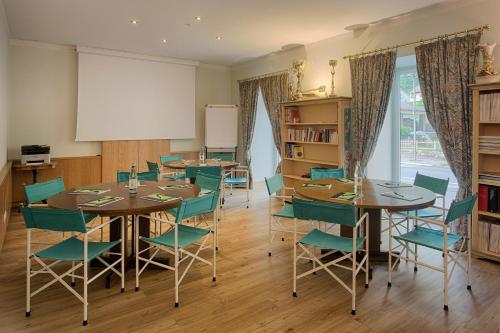 a dining room with tables and green chairs at Bellavista Relax Hotel in Levico Terme