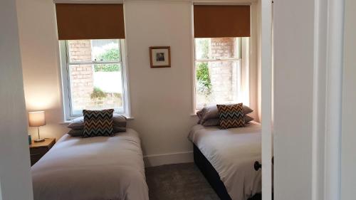 Beautiful Garden Apartment in Leafy St Leonards 5 Mins to Beach في سانت ليوناردز: سريرين في غرفة بها نافذتين