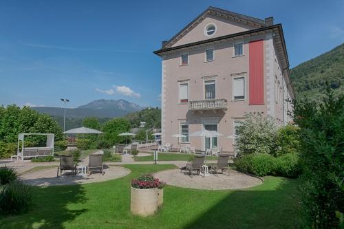 a large building with chairs and tables in a yard at Bellavista Relax Hotel in Levico Terme