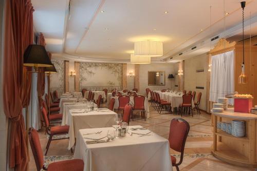a dining room with white tables and red chairs at Bellavista Relax Hotel in Levico Terme