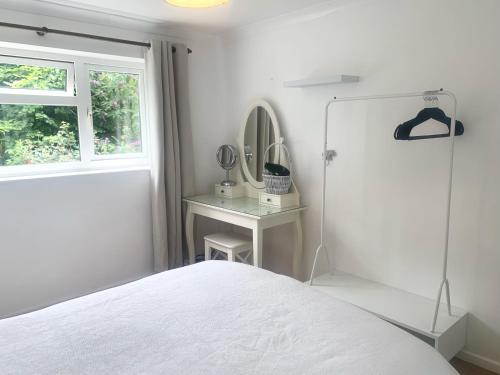 a white bedroom with a bed and a mirror at Penderels, Willersey in Broadway